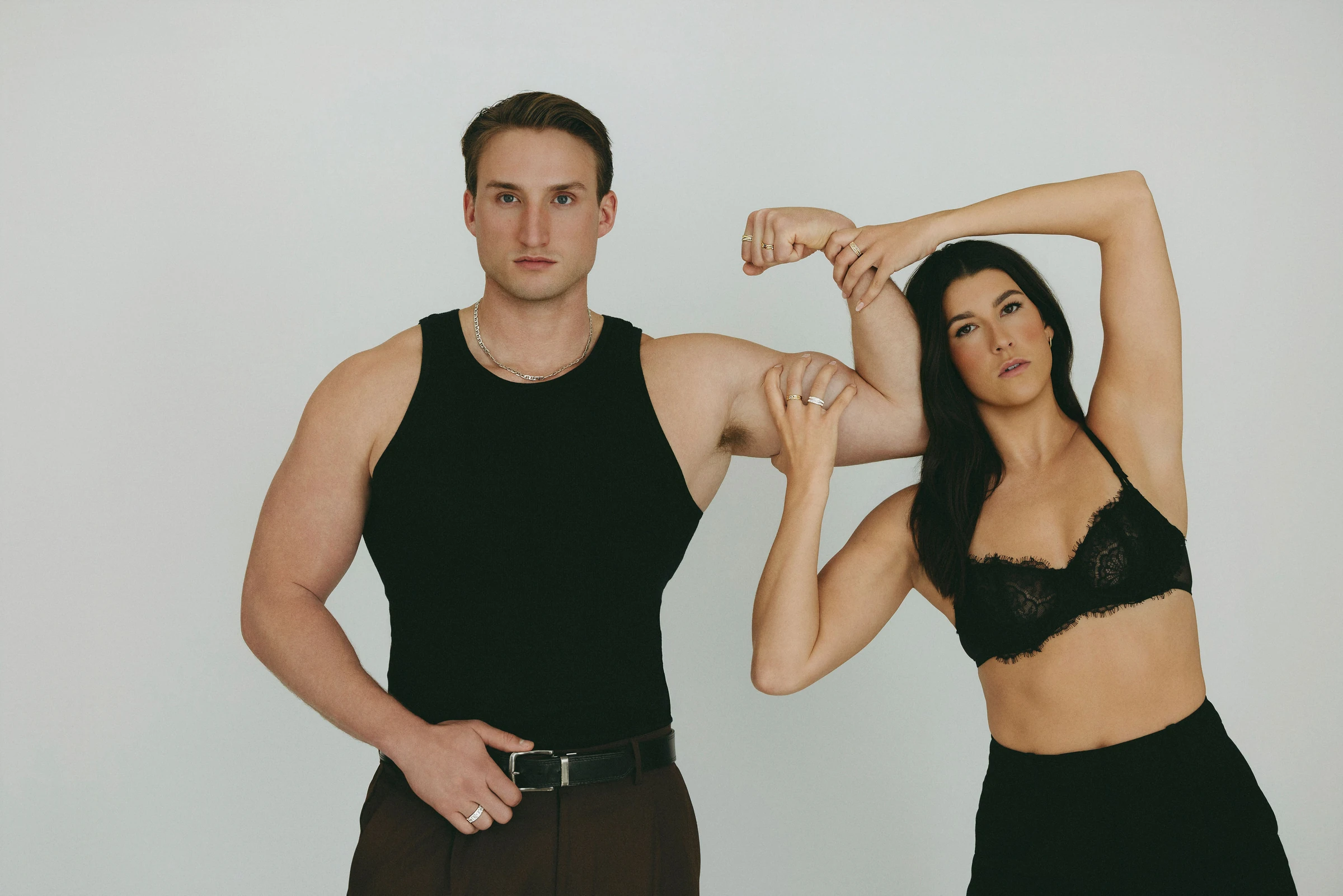 Two models in black, arms raised and linked, wearing rings