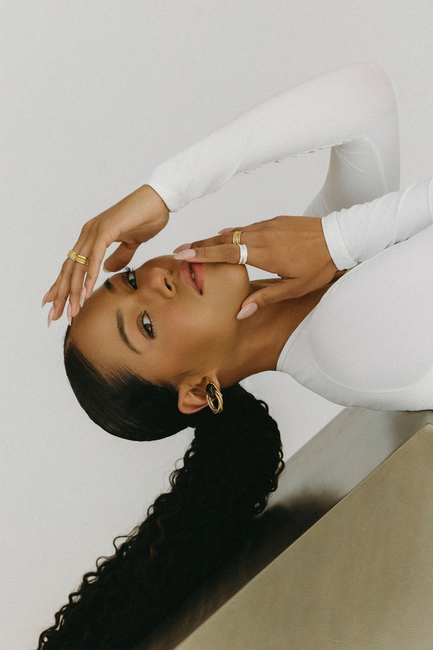 Model in white reclining on a plinth, wearing rings