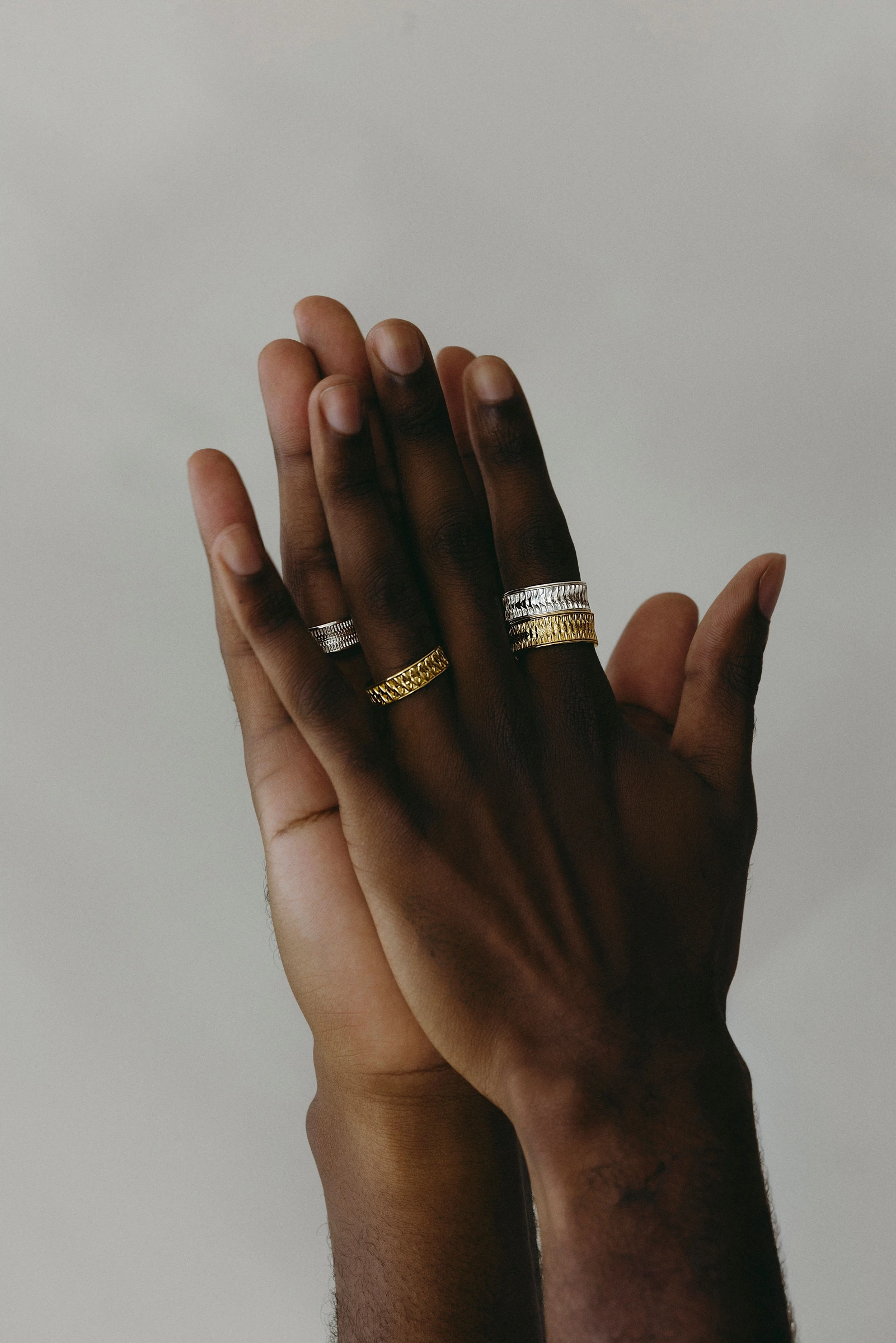 Hands together wearing sculptural rings