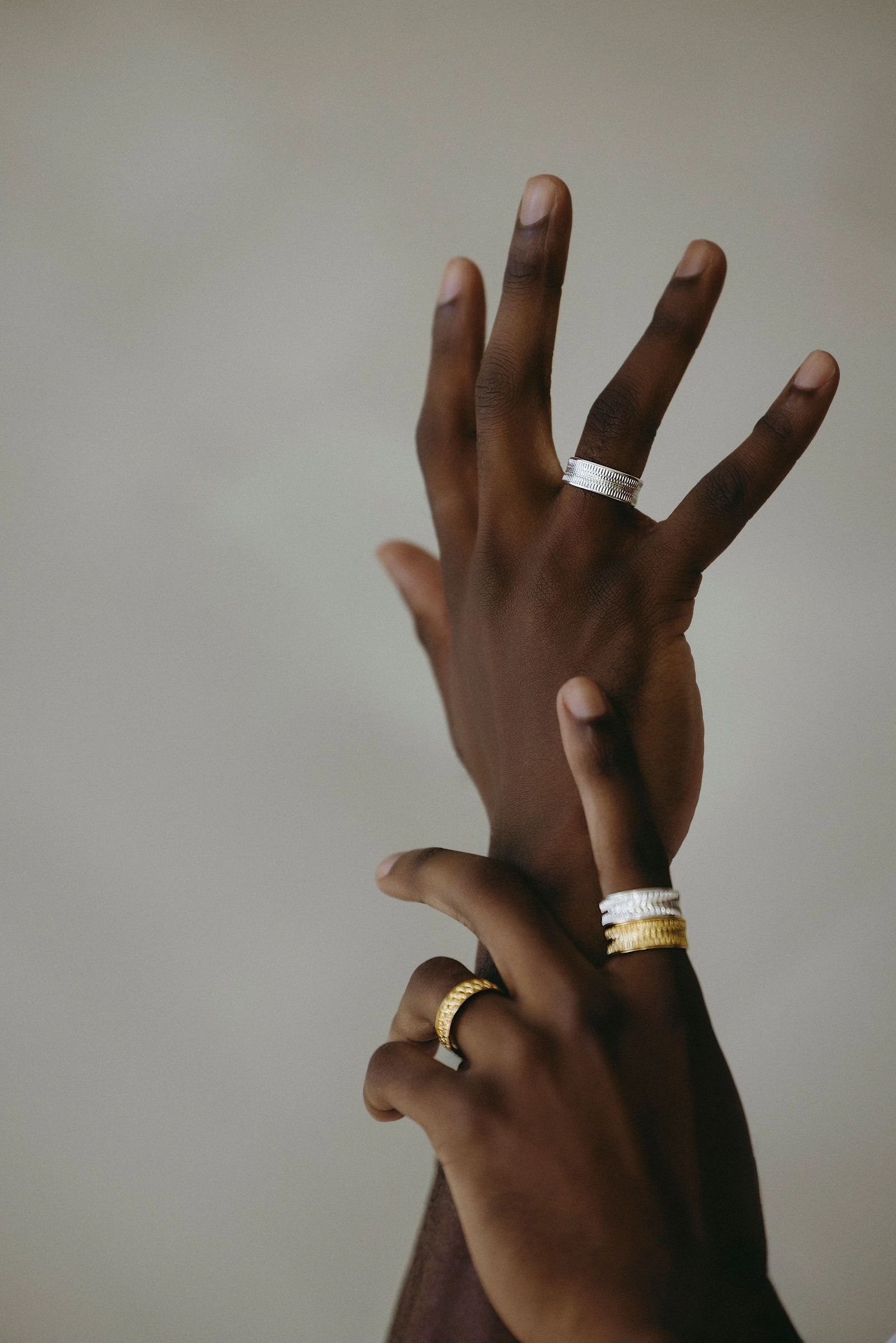 Raised hands wearing silver and gold rings