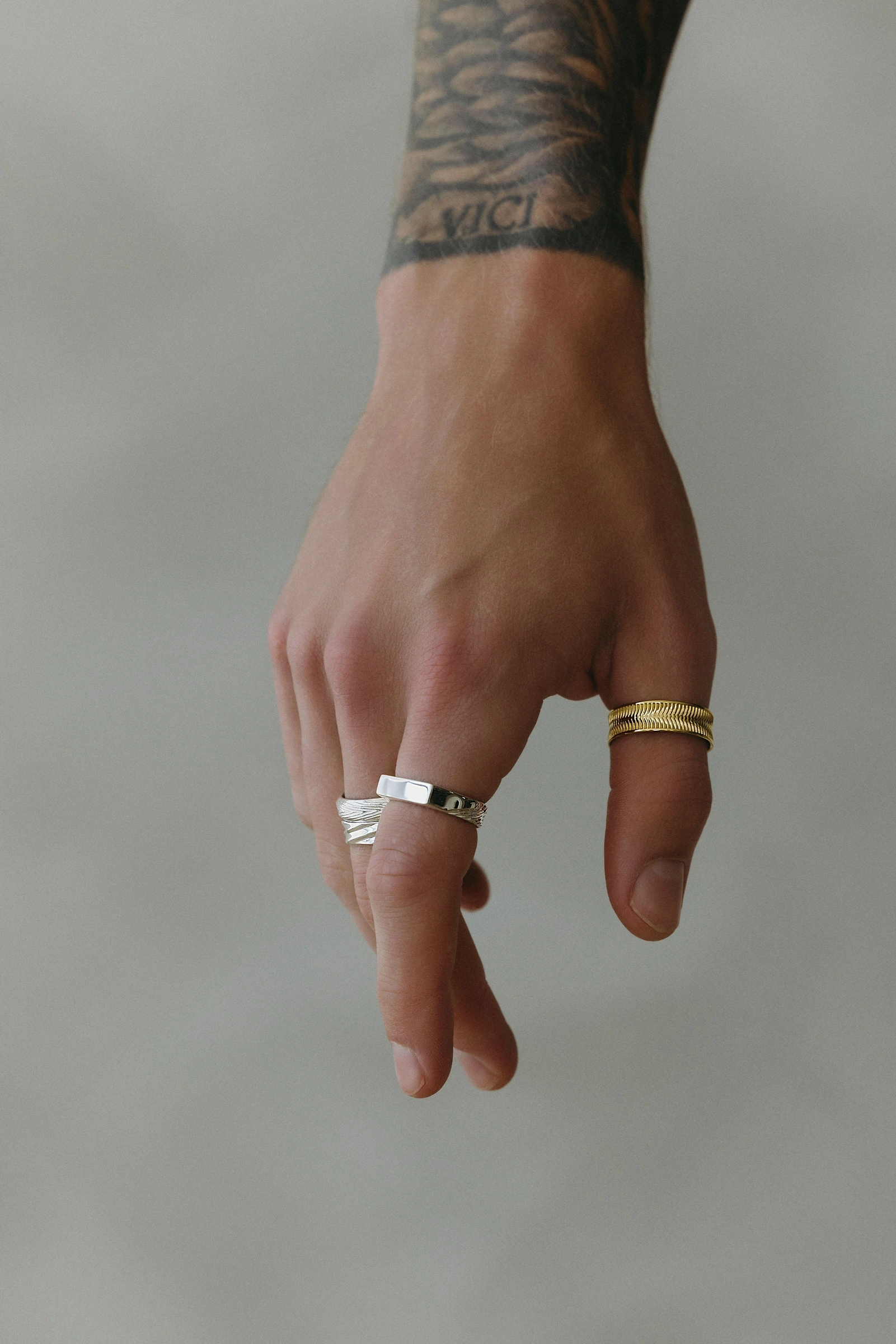 Close view of a tattooed arm and hand wearing rings