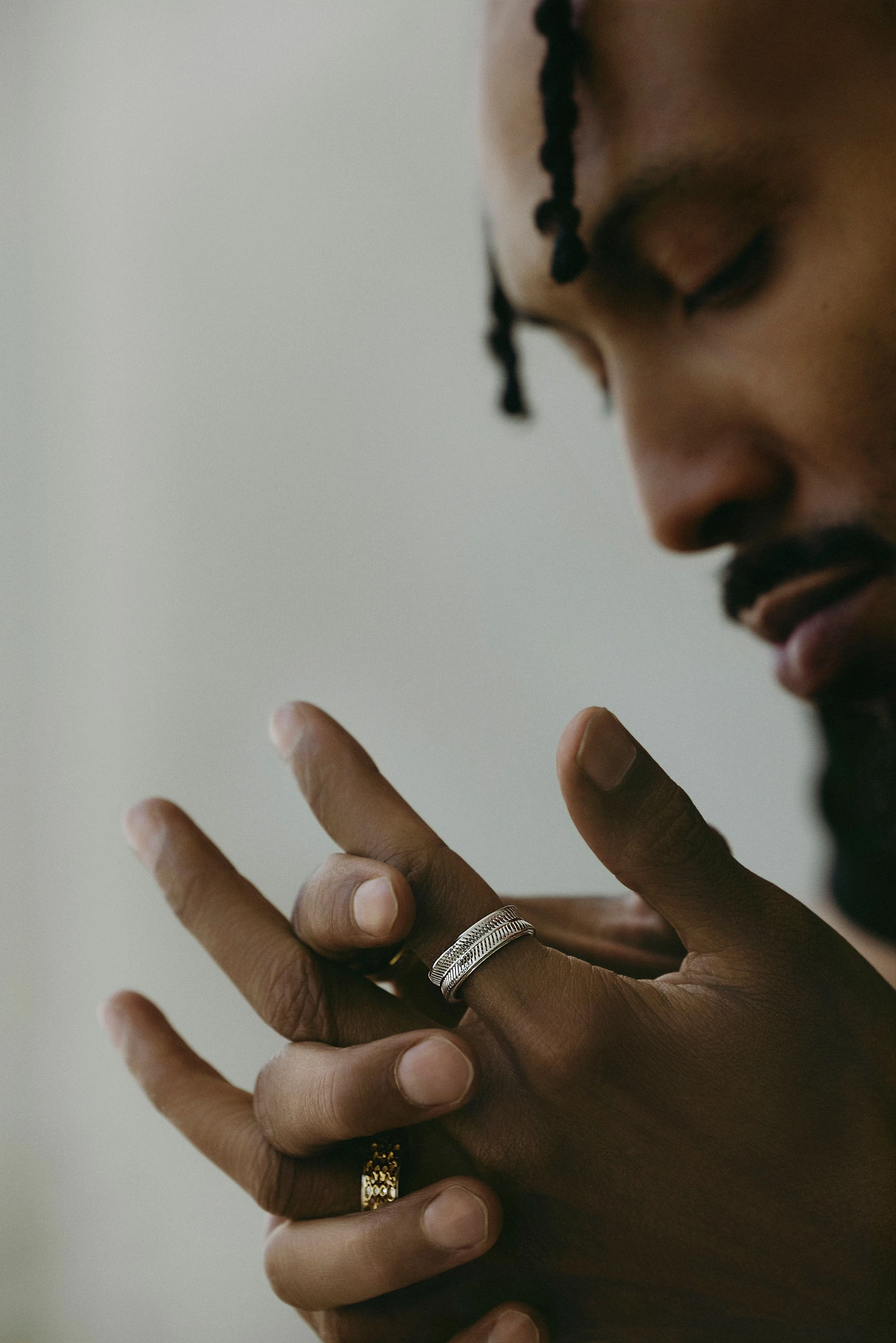 Model looking down at a hand wearing sculptural rings
